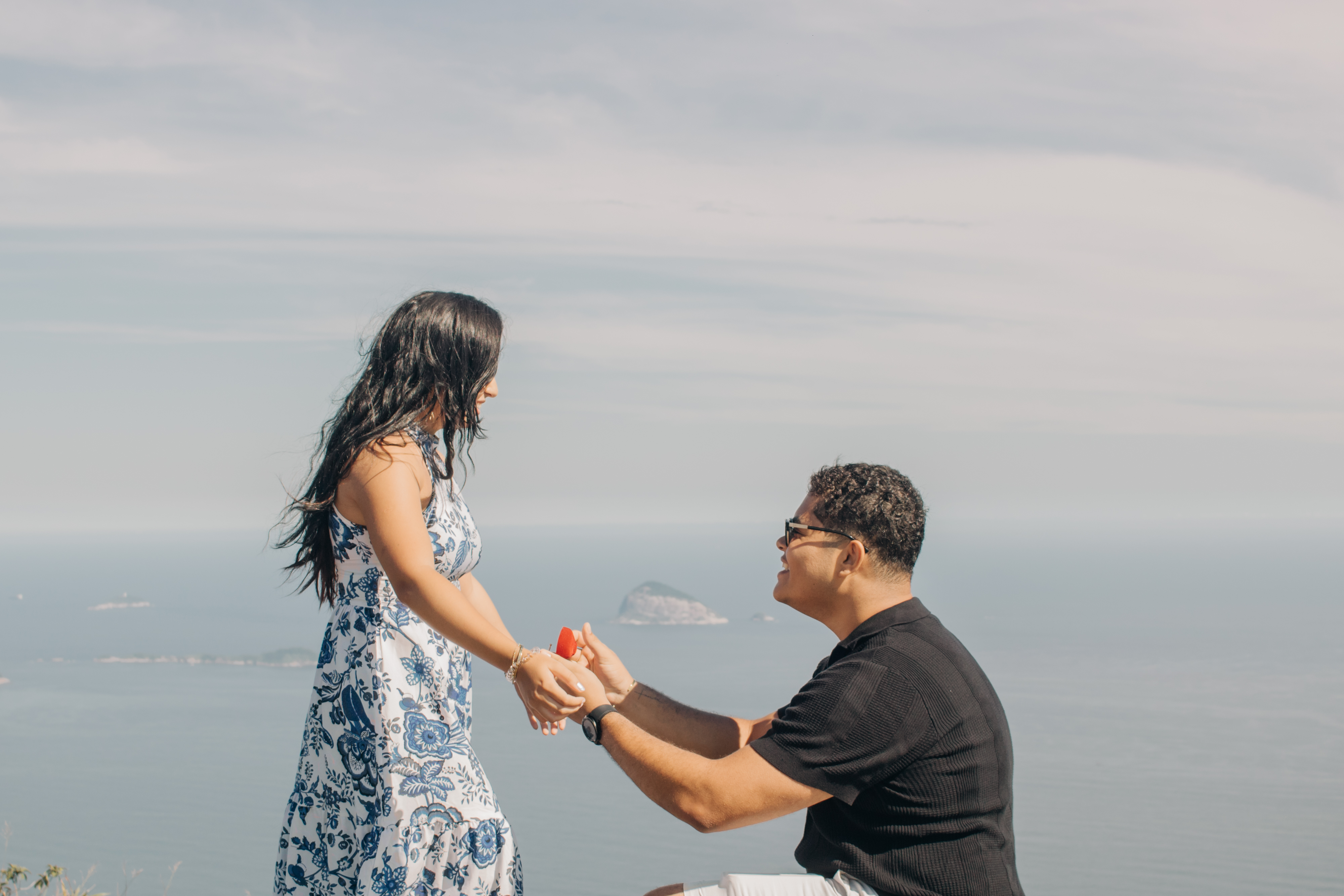 A man proposing to a woman on a cliff overlooking the sea.